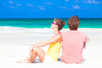 young happy couple sitting on tropical beach