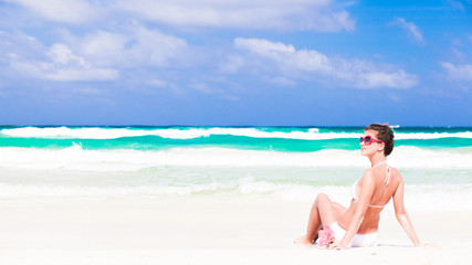 Fototapeta na wymiar young woman in bikini and sunglasses with flower sitting on