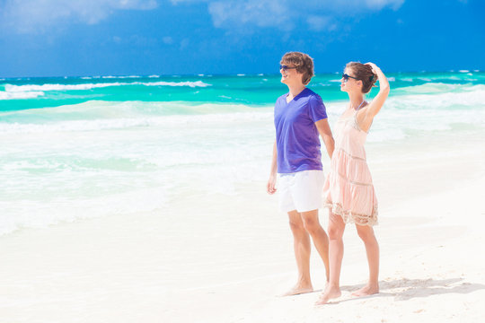 couple in bright clothes on tropical beach holding hands in
