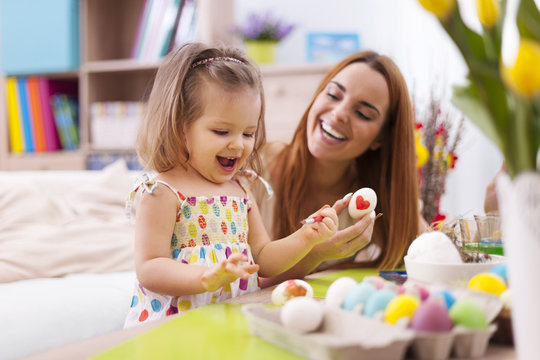 Loving mother and her baby painting easter eggs