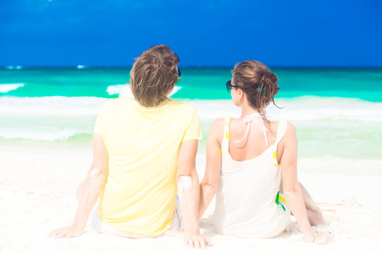 young happy couple sitting on tropical beach honeymoon