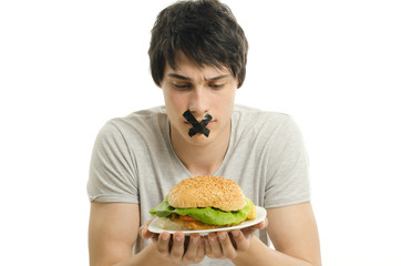 Man with tape on mounth unable to eat a big hamburger,dieting