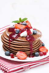 pancakes with cream and berries on a wooden table