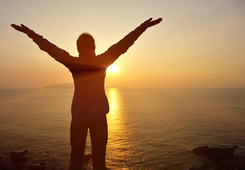 Fototapeta na wymiar cheering woman hiker open arms at sunrise seaside
