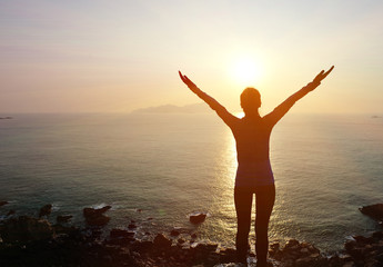cheering woman hiker open arms at sunrise seaside