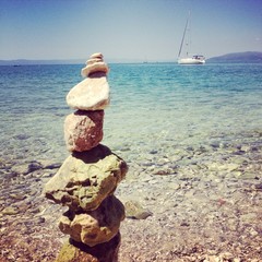 Pebbles on beach with yacht in background
