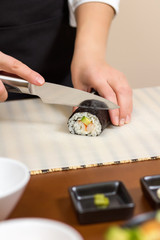 Obraz na płótnie Canvas Closeup of woman chef cutting japanese sushi roll