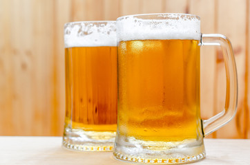 Two beer mugs on the wooden background