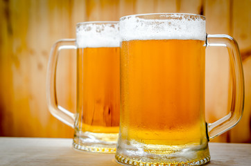 Two beer mugs on the wooden background