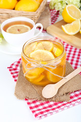 Tasty lemon jam with cup of tea on table close-up