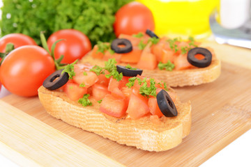 Delicious bruschetta with tomatoes on cutting board close-up