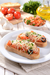 Delicious bruschetta with tomatoes on plate on table close-up
