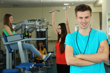 Young trainer and womans engaged in simulator in gym