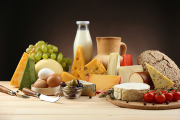 Tasty dairy products on wooden table, on dark background
