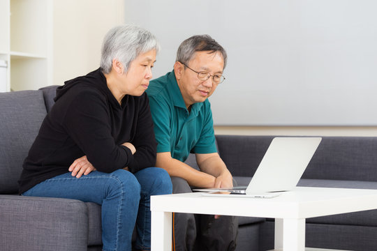 Elderly Couple Using Laptop Computer At Home