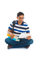 indian young male student surfing while sitting on the floor