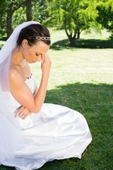 Female bride sitting on grass in park