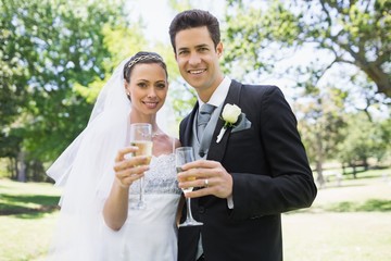 Newlywed couple toasting champagne in park