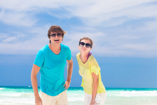 Portrait of happy young couple in sunglasses smiling on beach
