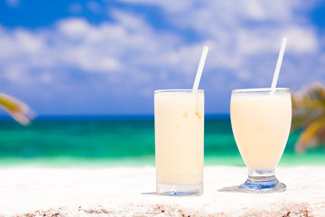 picture of two white cocktails on tropical beach with palms on