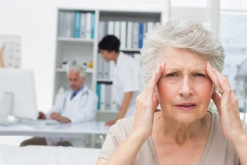 Senior patient suffering from headache with doctors at medical