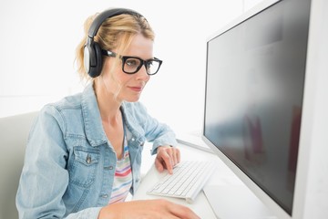 Blonde designer wearing headphones working at computer