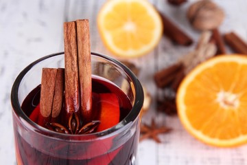 Mulled wine with oranges and spices on wooden background