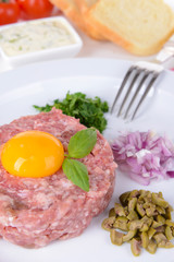 Delicious steak tartare with yolk on plate on table close-up