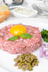 Delicious steak tartare with yolk on plate on table close-up