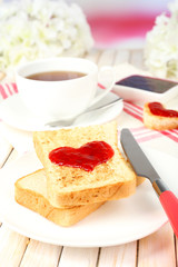 Delicious toast with jam and cup of tea on table close-up