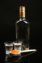 Bottle of vodka, red caviar  isolated on black