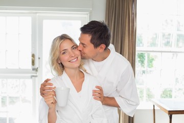Loving young man kissing woman's cheek at home