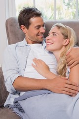 Loving couple looking at each other while lying on sofa