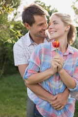 Fototapeta premium Young couple holding a flower in the park
