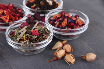 Aromatic dry tea in bowls on wooden background