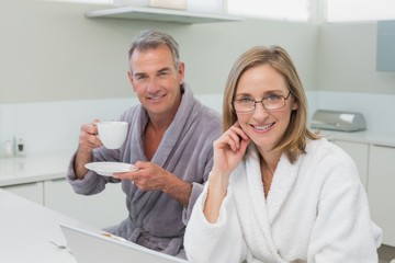 Couple having breakfast while using laptop in kitchen