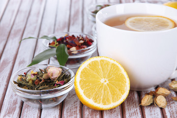 Cup of tea with aromatic dry tea in bowls on wooden background
