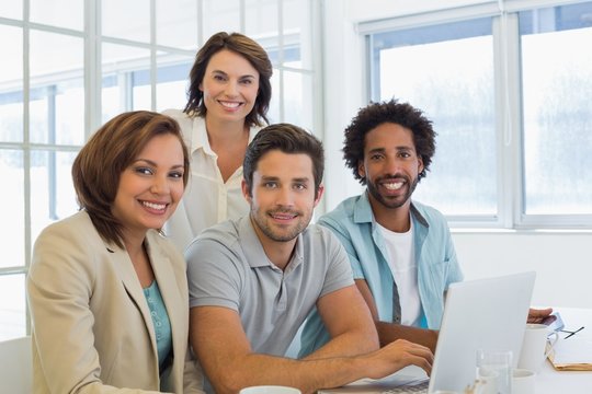 Smiling business people using laptop in meeting
