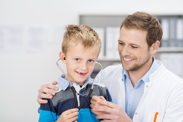 kleiner junge beim arzt hört mit dem stethoskop