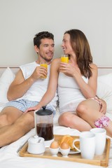 Happy couple having breakfast in bed