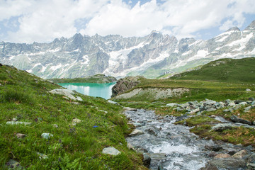 Naklejka na ściany i meble Creek flowing into the lake on a background of mountains