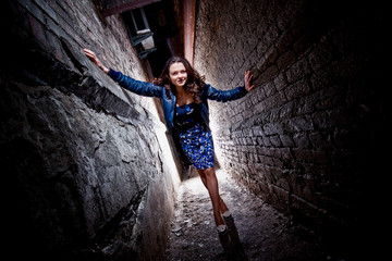 Beautiful stylish woman posing between two brick walls at night