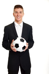 Young smiling businessman at suit holds a soccer ball
