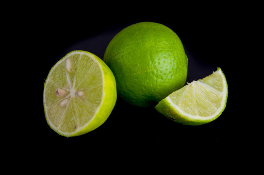 Citrus lime fruit half on black background, small green lemons