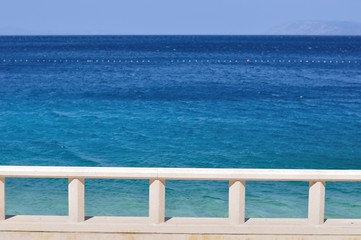 Fototapeta na wymiar Blue adriatic sea with white banister in Podgora, Croatia