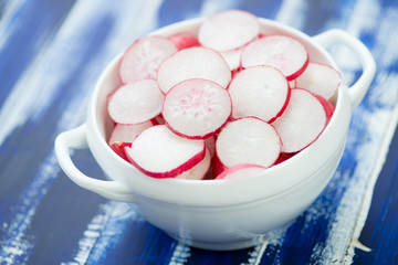 Glass bowl with radish sliced in circles, close-up