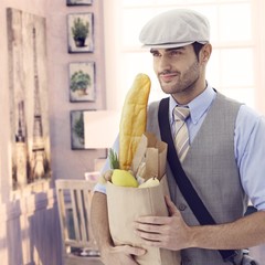 Handsome man holding grocery bag at vintage home
