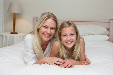 Woman with daughter lying in bed at home