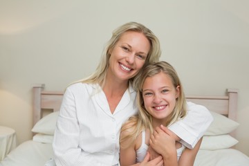 Mother and daughter sitting in bed at home