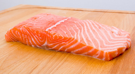 Uncooked salmon fillet on a wooden board